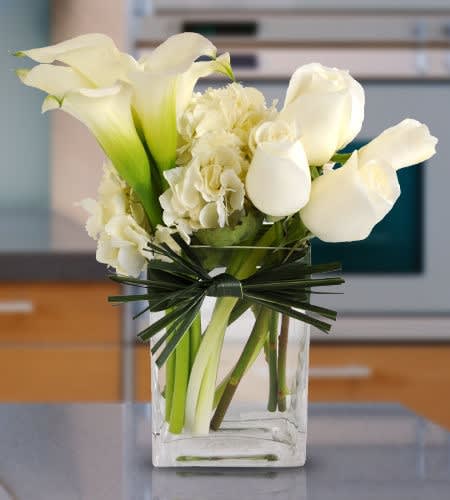 White roses, calla lilies and hydrangea complimented with green leaf bow. A