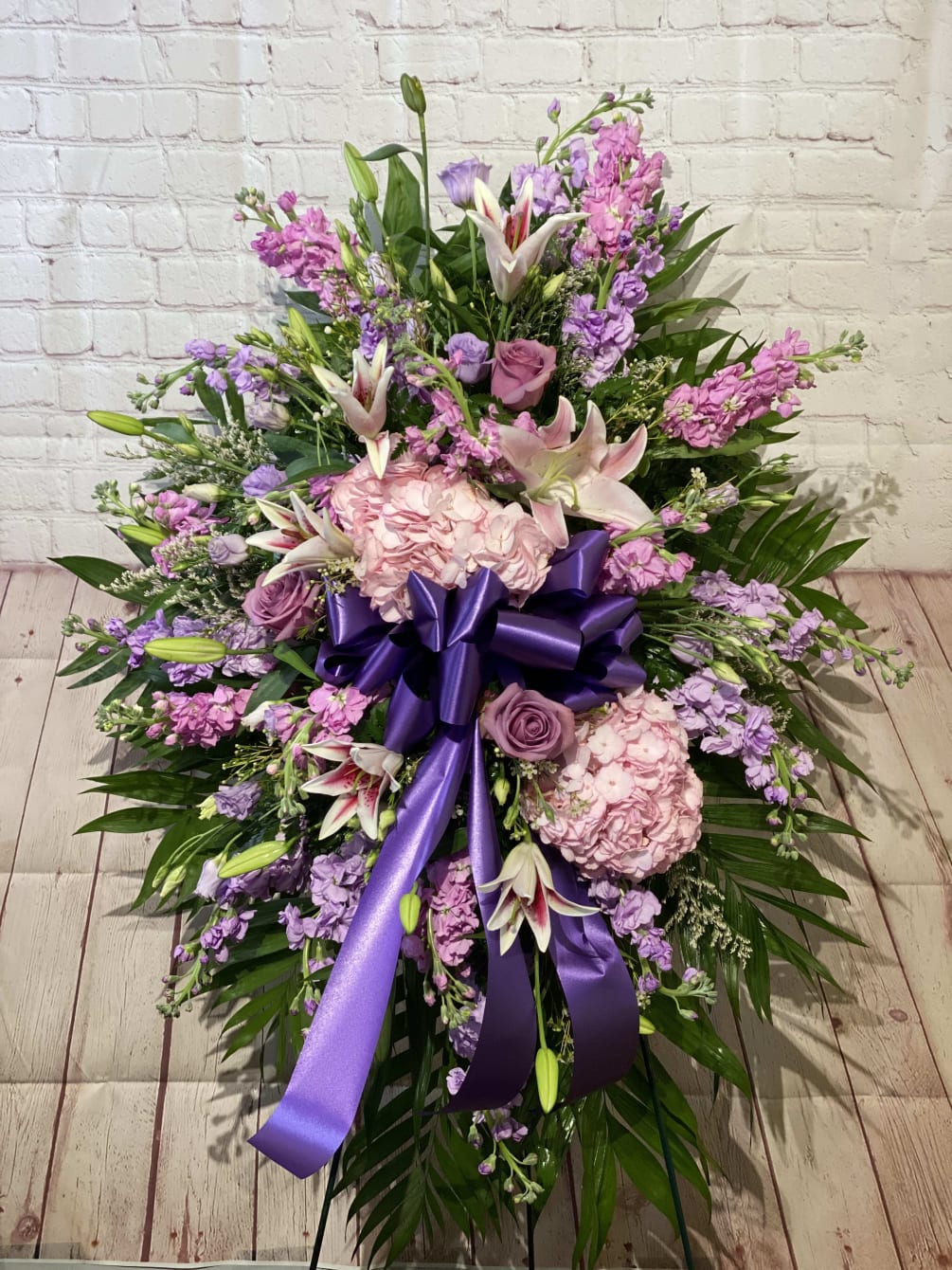 This gorgeous standing sympathy spray combines lilies, hydrangea, and dahlias in pinks