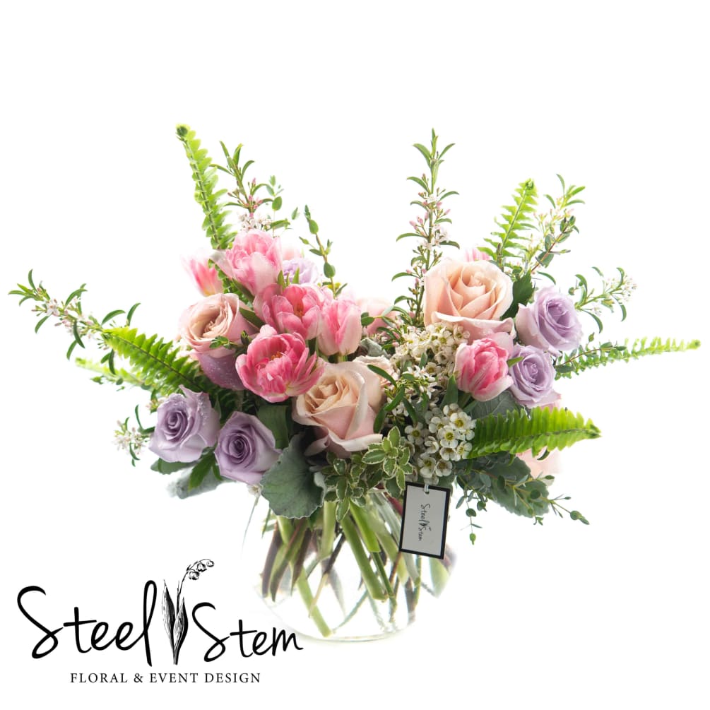 A lovely vase arrangement featuring pastel pinks and lavenders that includes premium