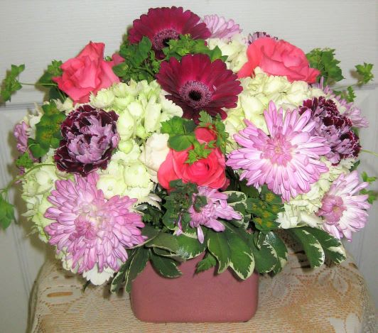 Bright florals with fizz! Red gerbera daisies, hydrangia, purple mini carnations and
