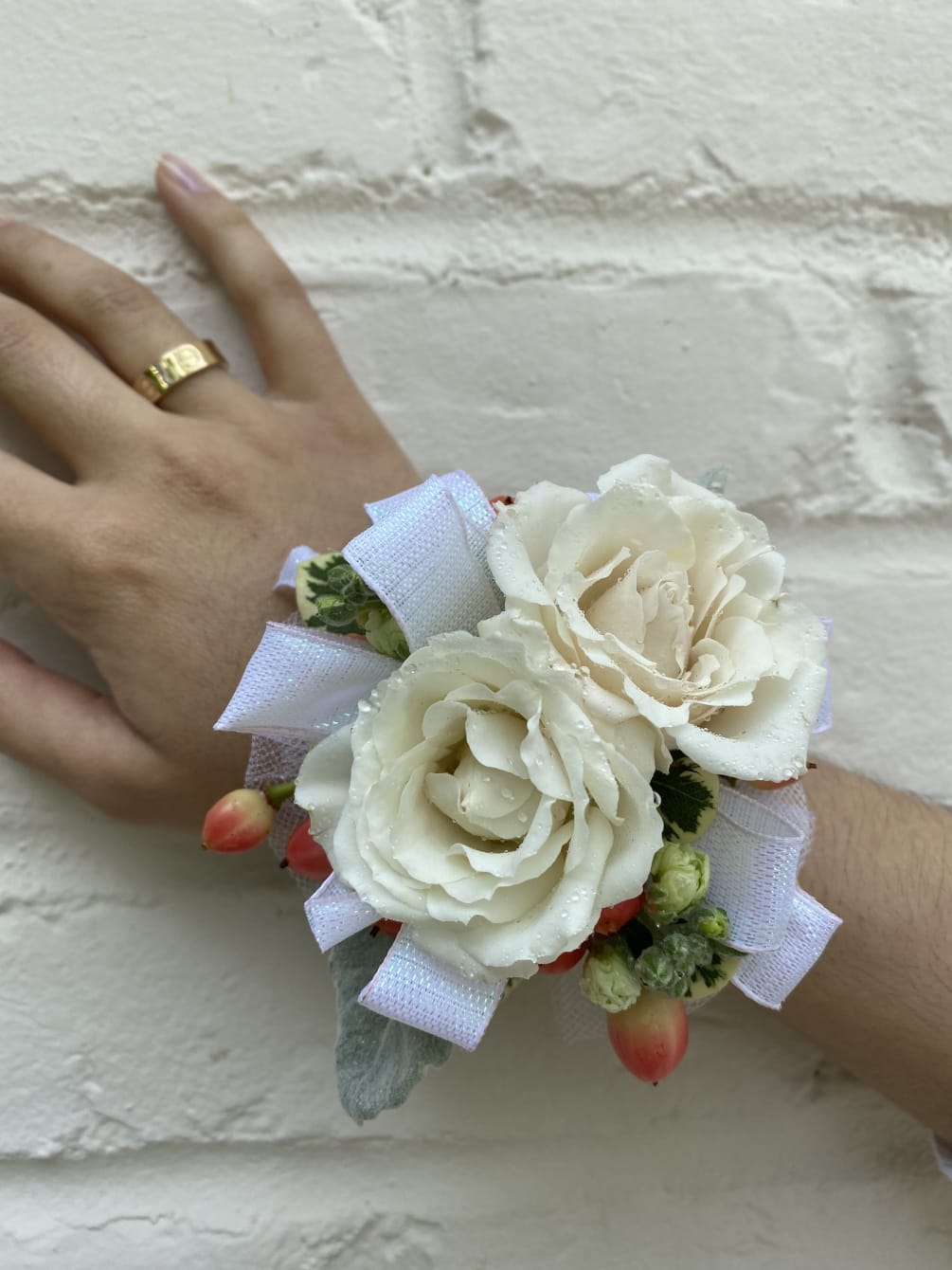 An elegant and simple corsage of white spray roses and hypericum berries.