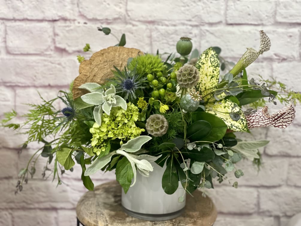 An earthy bouquet of luxurious foliage, interesting green florals and preserved elements.