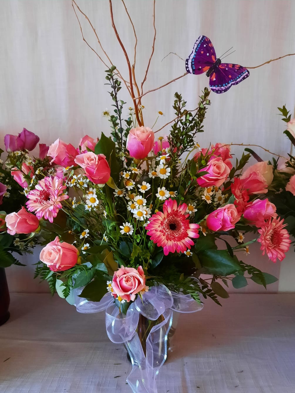 Two dozen beautiful pink roses adorned with decorative butterfly, willow wood and