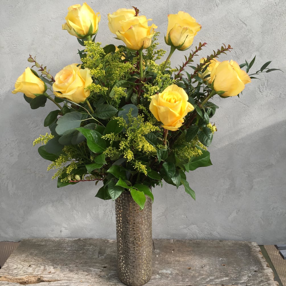 A dozen long stem DejaVu yellow roses arranged in a vase.