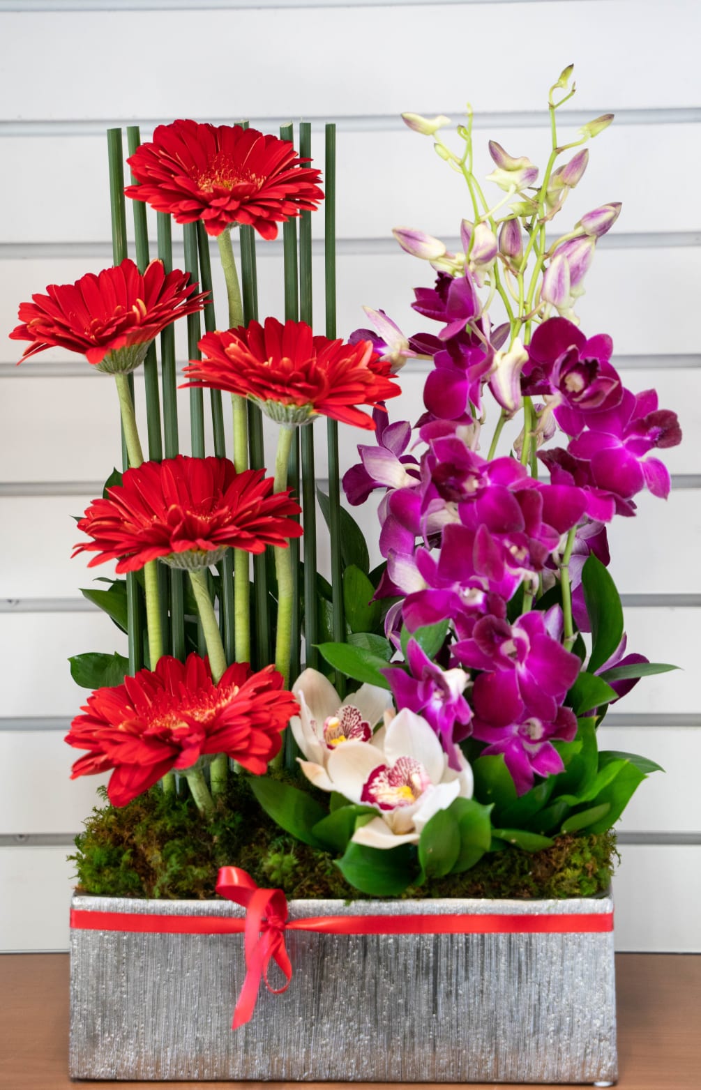 A vertical design of gerbers, dendrobium orchids, cymbidium orchid blooms in a