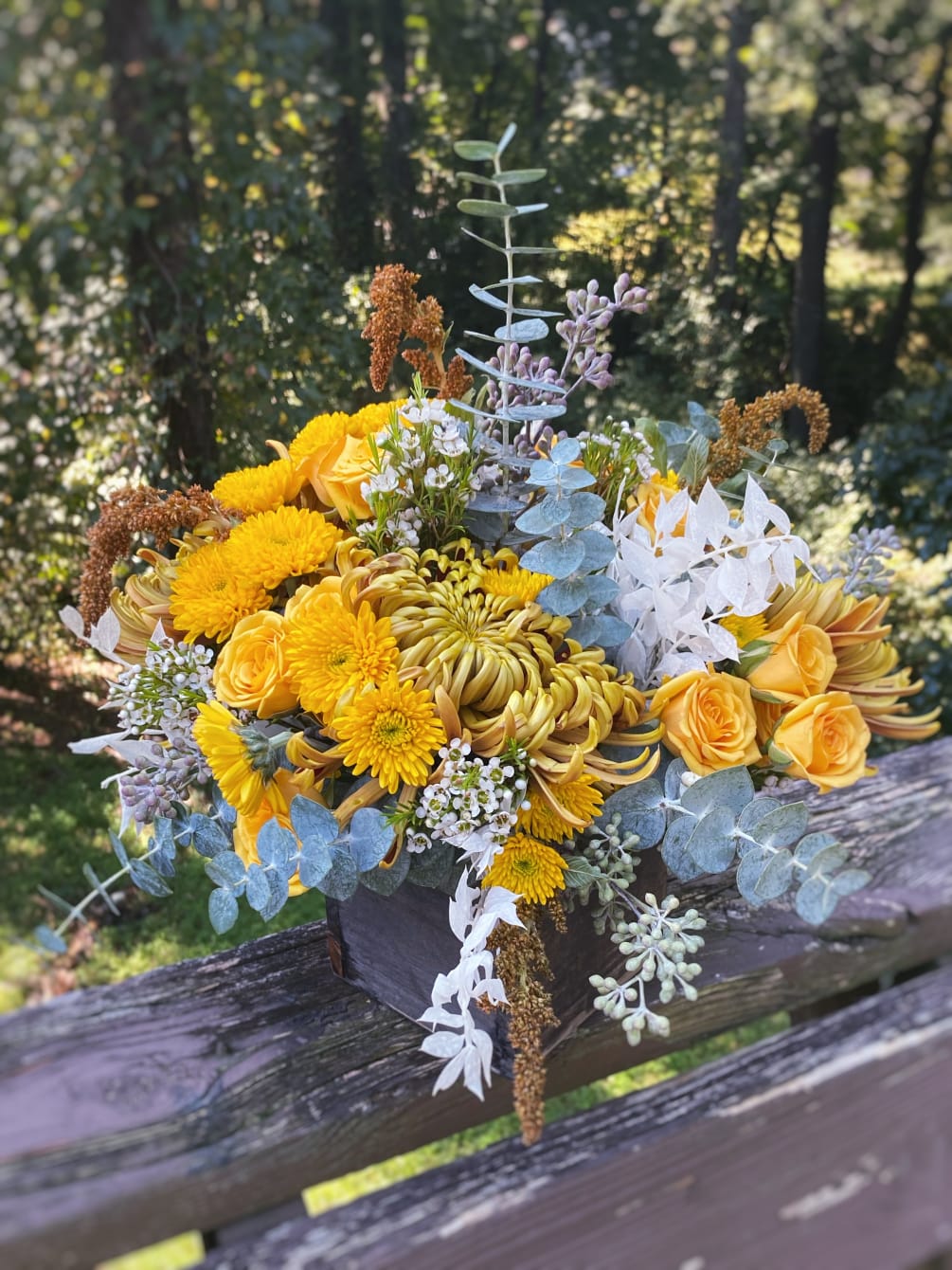 Tightly arranged flowers in a wooden box. Color palette varies throughout the