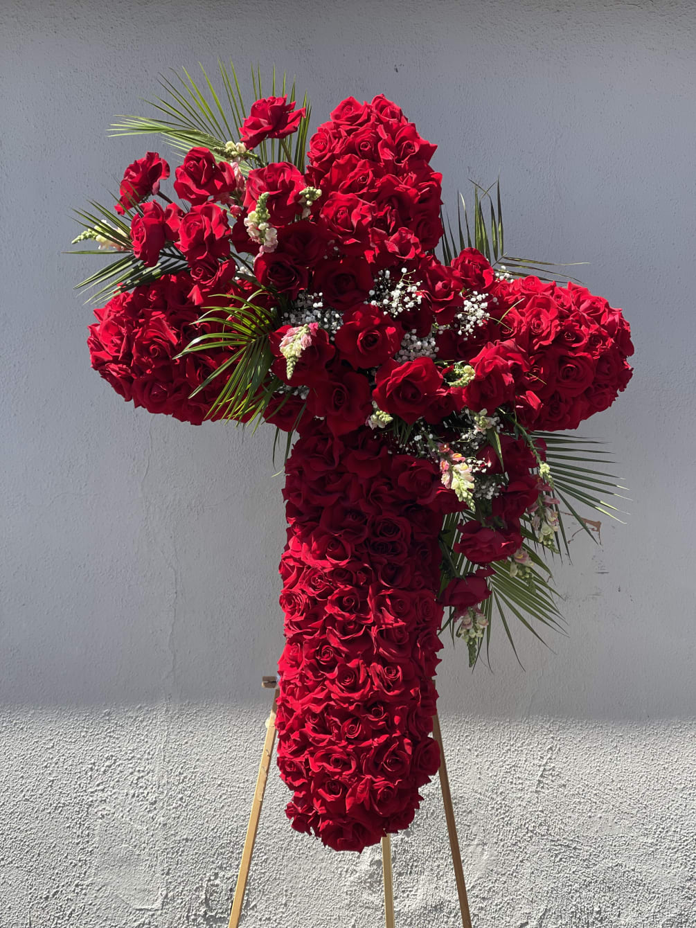 A 42 inch red rose cross with a beautiful arrangement in the