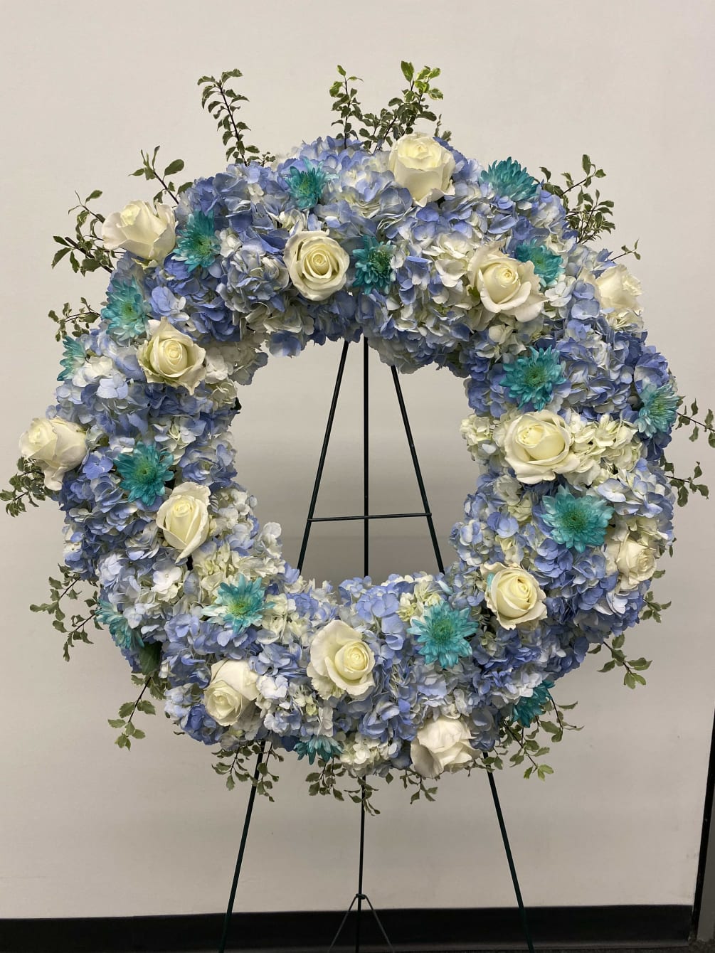 Very large wreath of hydrangeas, roses and greenery. Colors are Light blue
