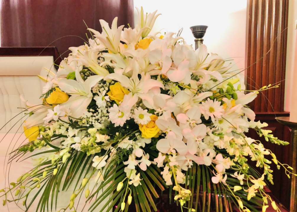 Beautiful yellow and white casket arrangment featuring lilies, orchids, daises, baby breathe
