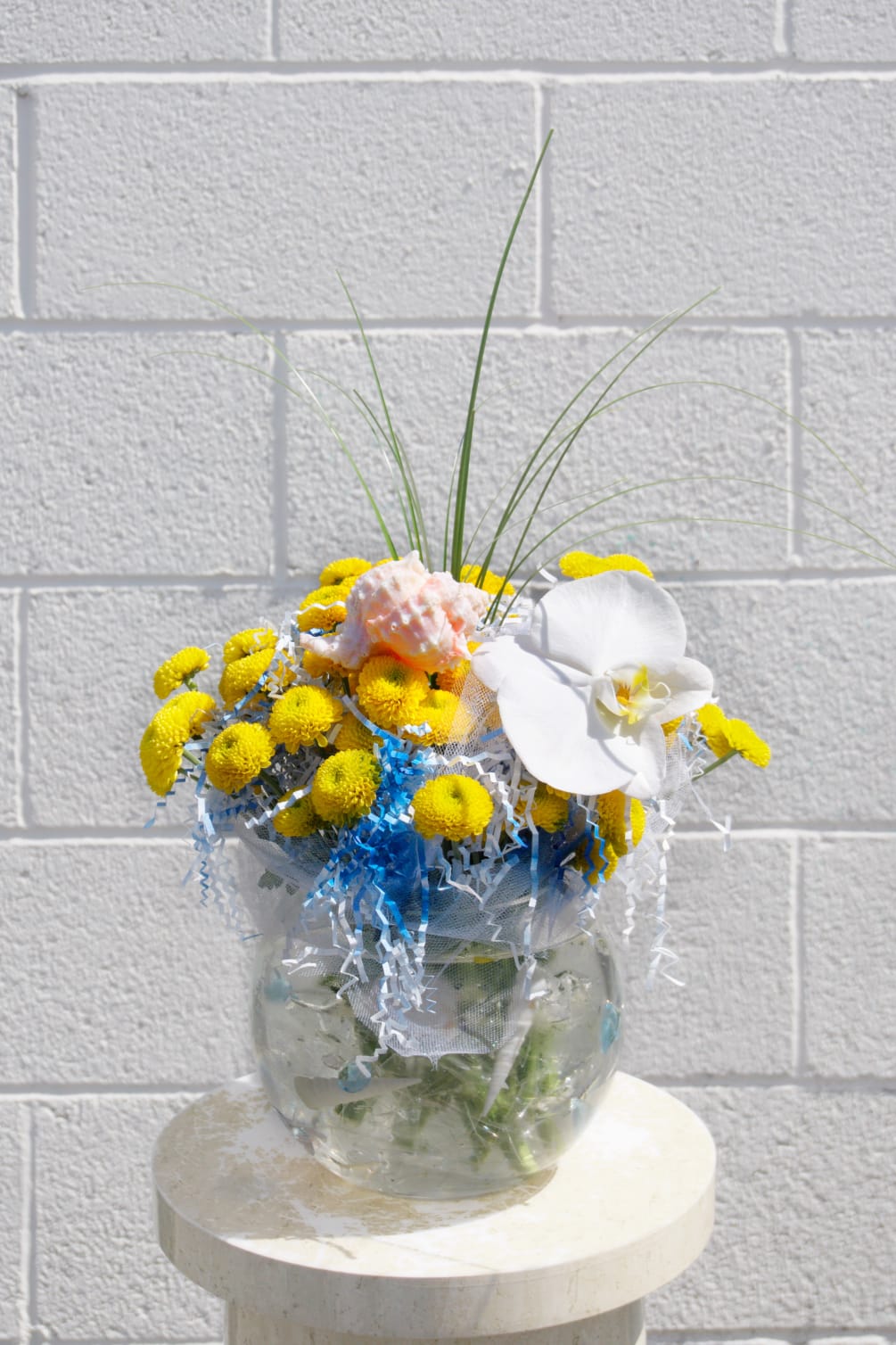 Oceanic design including yellow buttons, roses, orchids, sea holly, sea shells and
