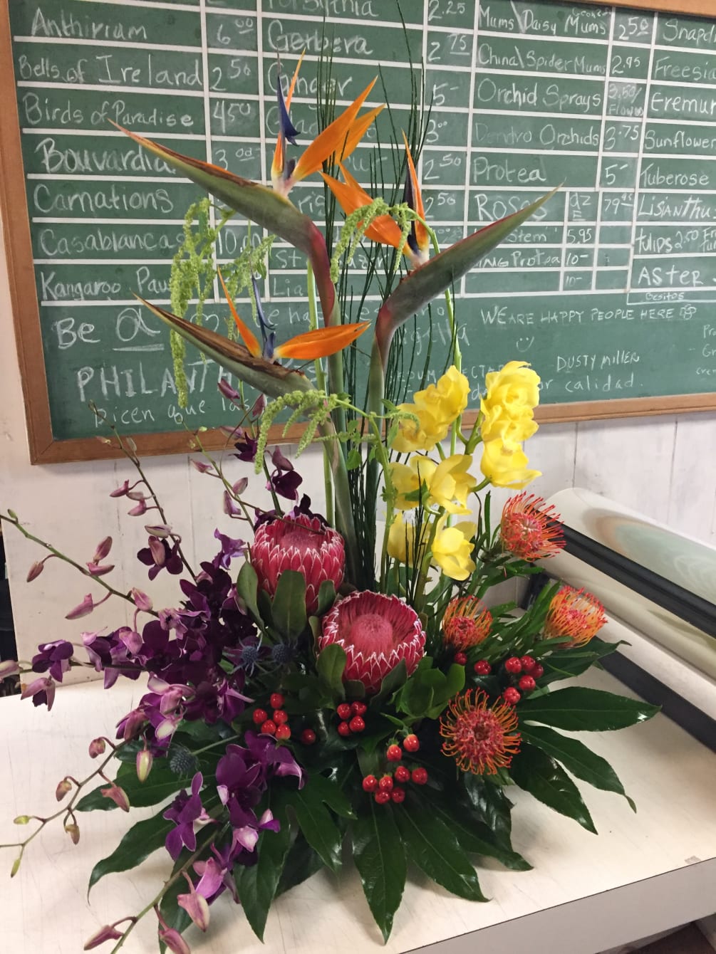 Exotic floral arrangement with orchids, birds of paradise, and protea. 