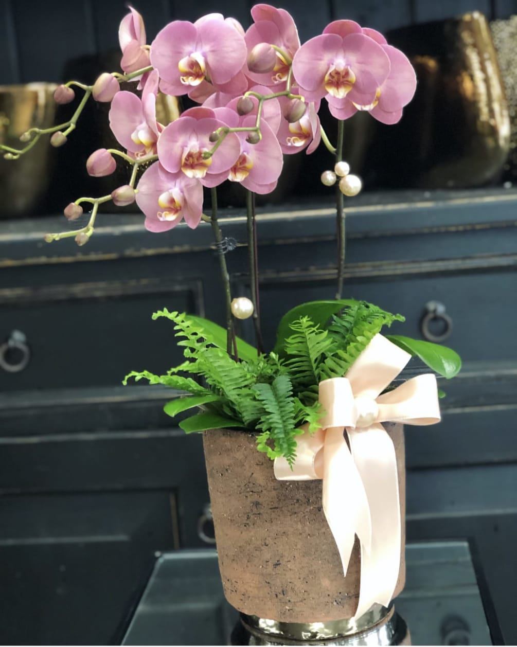 An assortment of dusty rose phalaenopsis orchids accented with ribbon and pearls