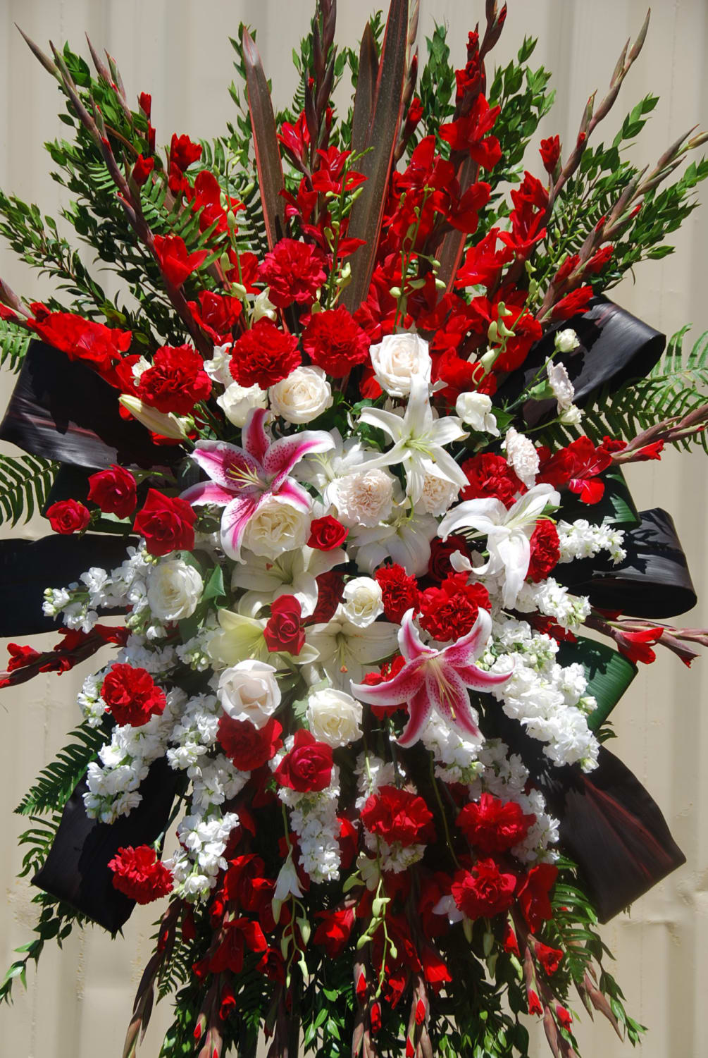 A large sympathy spray arrangement with red carnations, mixture of roses and