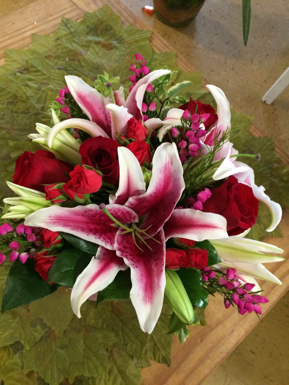 Stargazer lilies, with roses, spray roses, and seasonal filler.