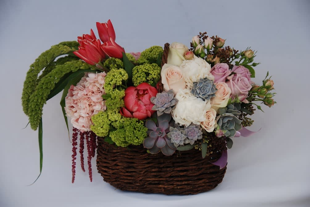 This unique basket is filled with tulips, hydrangeas, lavender roses, pink spray