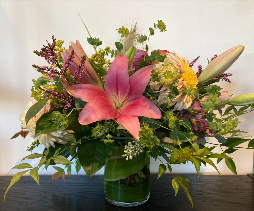 A beautiful assortment of early fall flowers including lilies and dahlias designed
