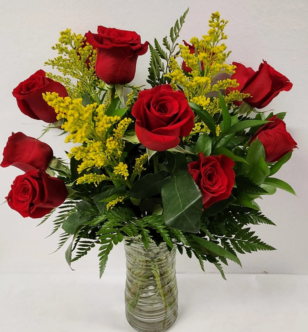 A dozen roses arranged in a traditional style with dainty filler flowers