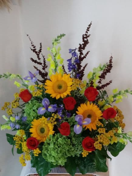 A Basket filled with Sunflowers,Iris,Red Roses, Bells of Ireland,Yelliow Alstromeria and assorted