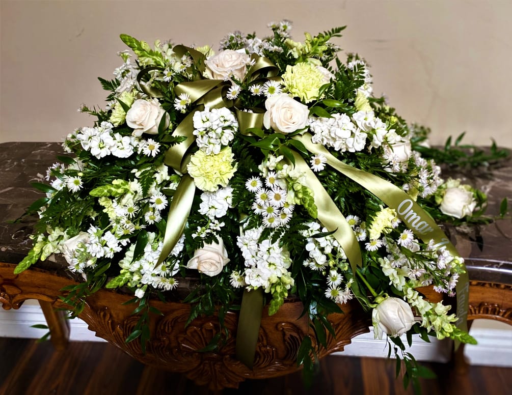 This delicate casket spray is composed of various White &amp; Green Blooms.