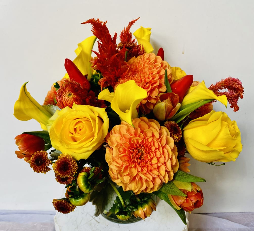 IN A GLASS VASE COMBINATIONS OF YELLOW AND ORANGE FLOWERS
