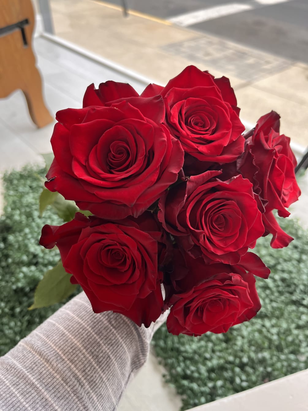 6 red roses arranged in a handheld bouquet, finished with fresh greenery