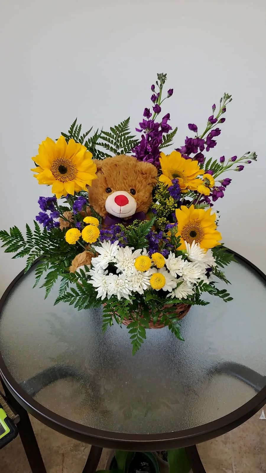Arrangement with sunflowers and a plush bear inside