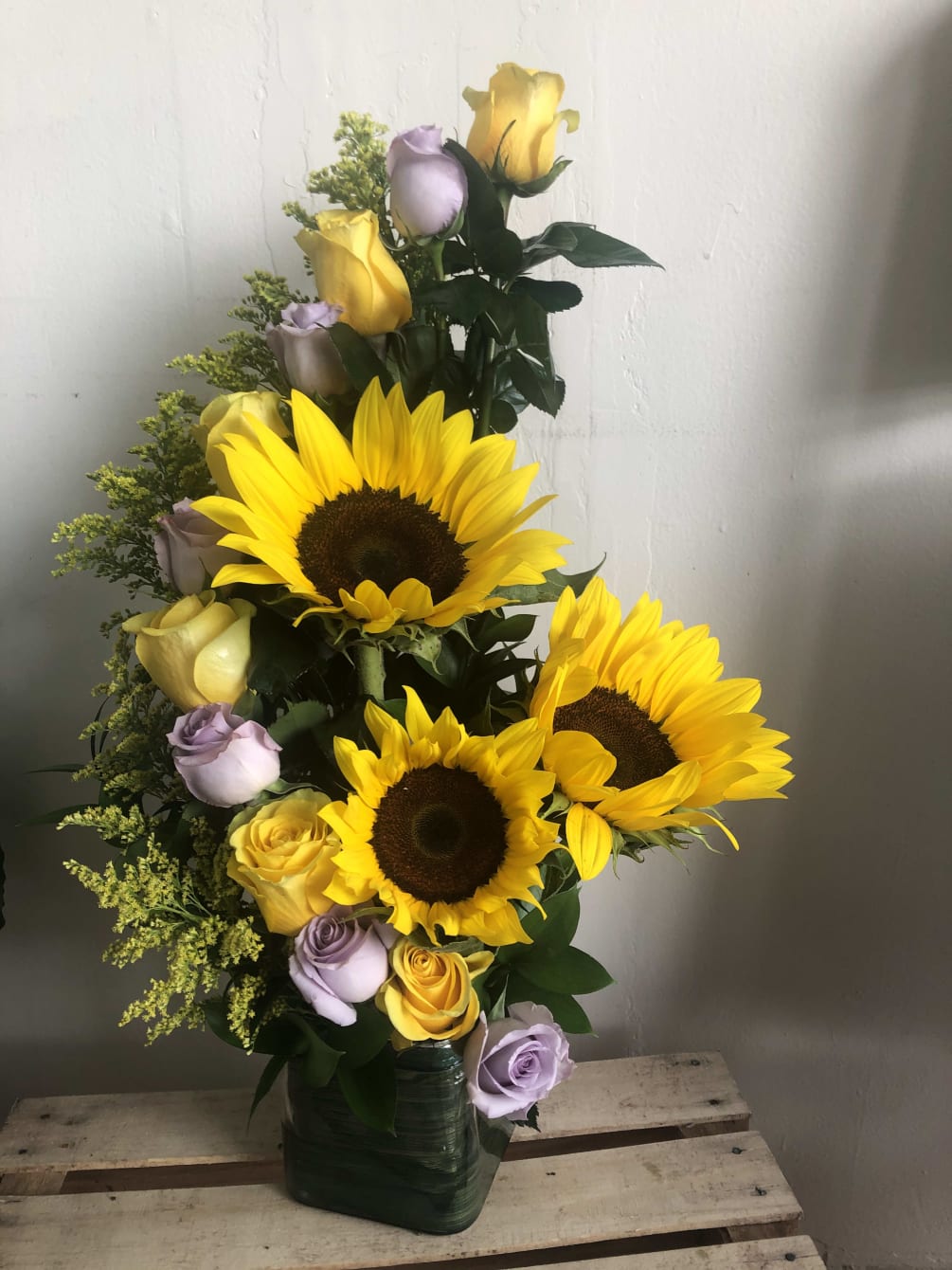 Combination of yellow and purple roses with three sunflowers in the Middle