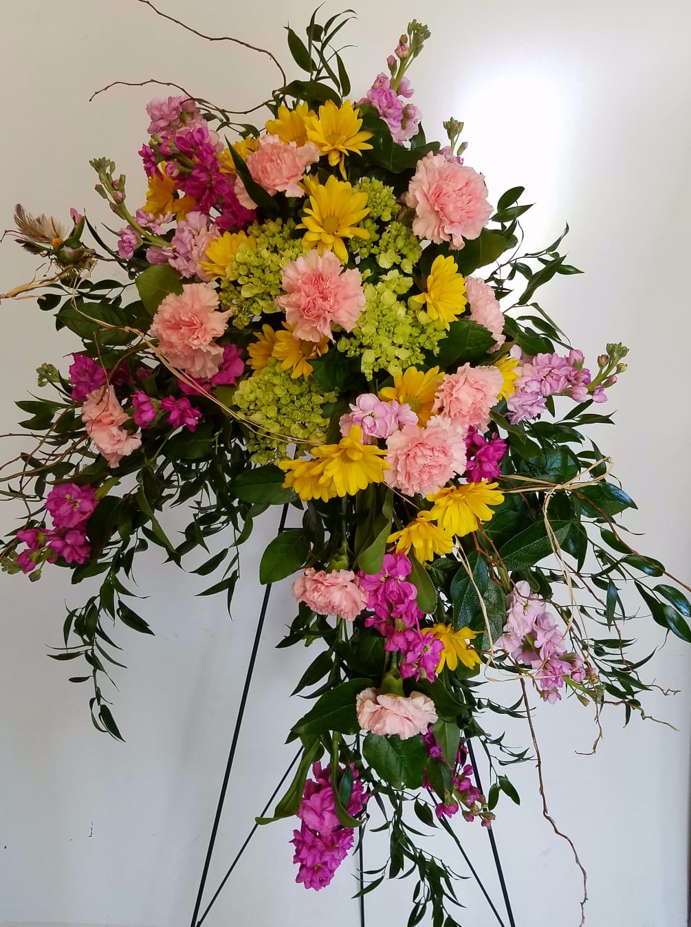 This crescent style floral tribute features green hydrangeas, pink carnations,
yellow daisies and
