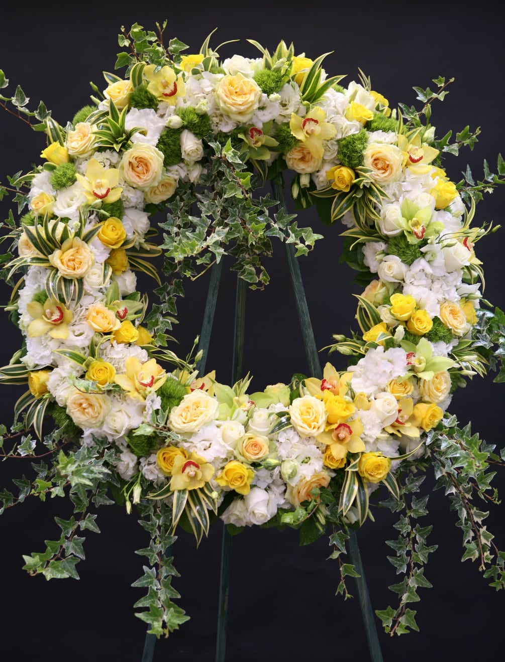 Grand sympathy wreath composed of yellow and white roses, cymbidium orchids, moss