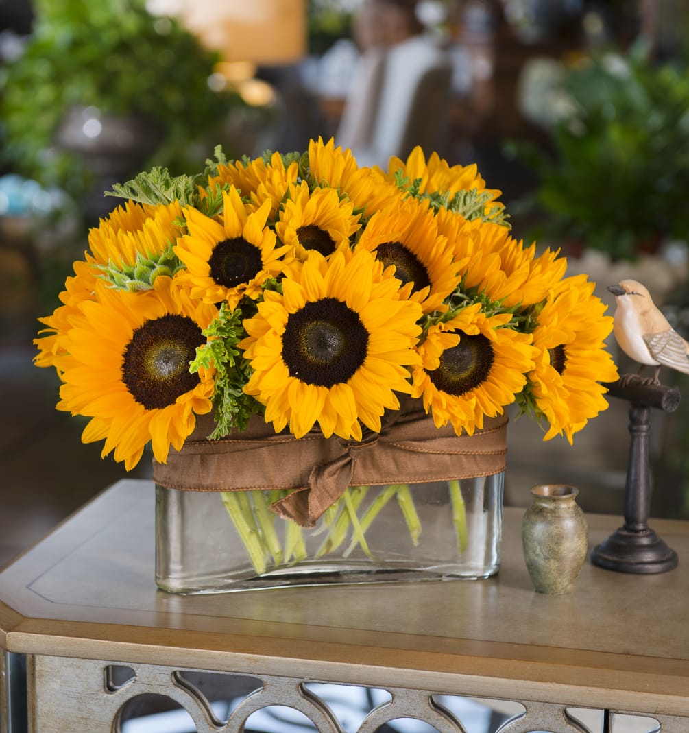 A mix of our freshest cut sunflowers in a rectangular glass vase.