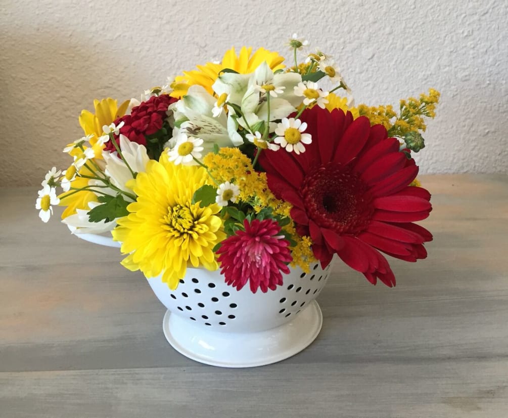 Red and yellow gerbera daisies in a short ceramic vessel. 