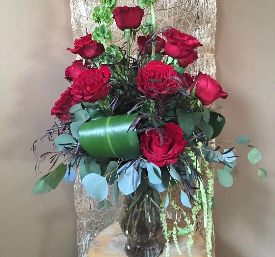 Red roses with eucalyptus and green accents. This beautiful arrangement evokes the