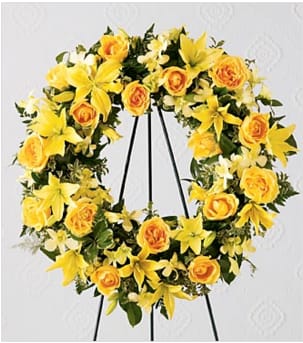 The FTD&reg; Ring of Friendship&trade; Wreath holds golden yellow roses, Asiatic lilies