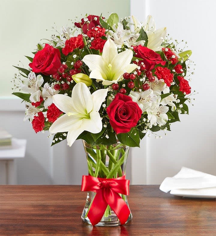 All-around arrangement with red roses and mini carnations; white Asiatic lilies and