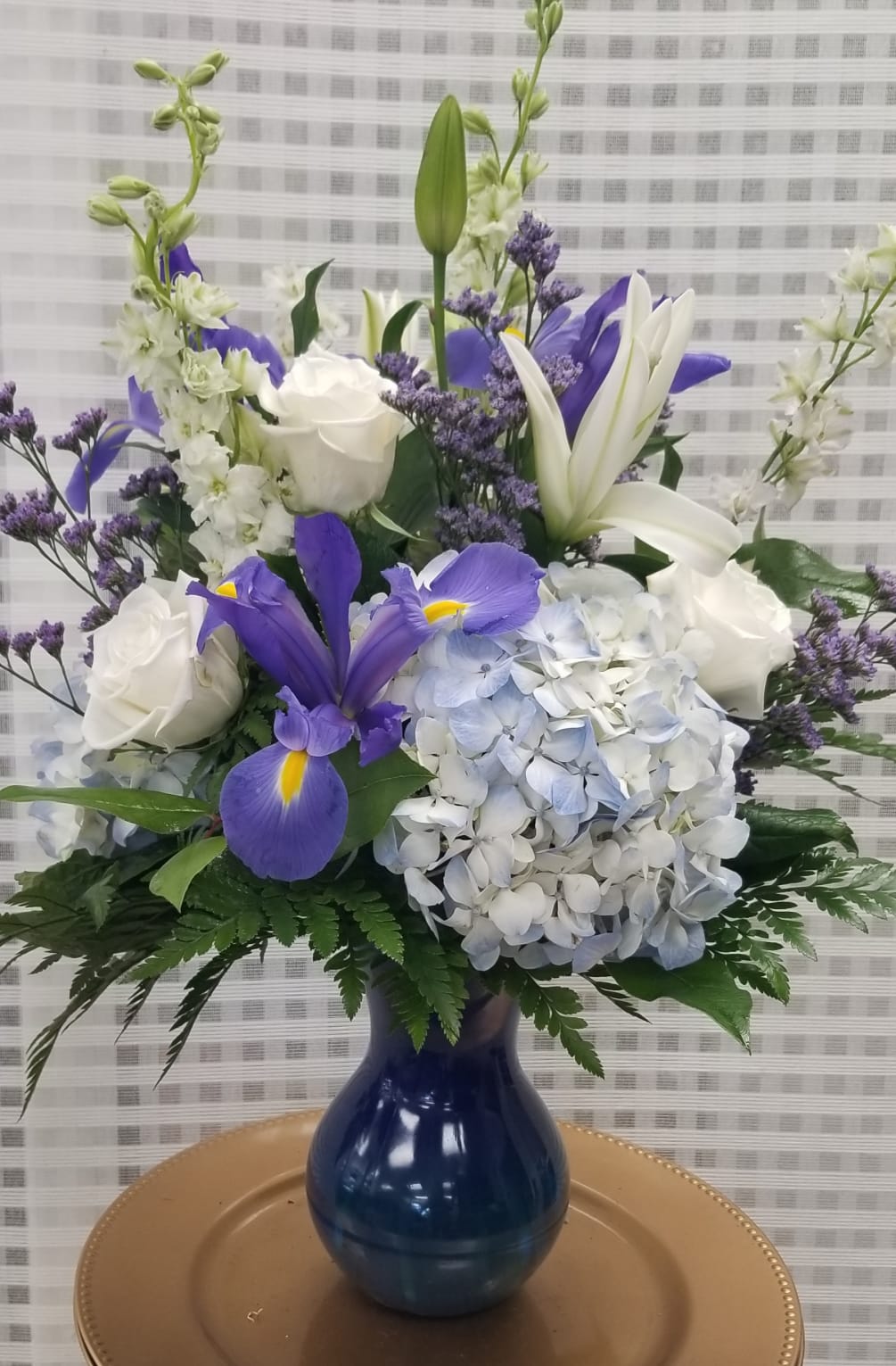 An arrangement of fresh blue hydrangea, iris, white roses, white lilies. 