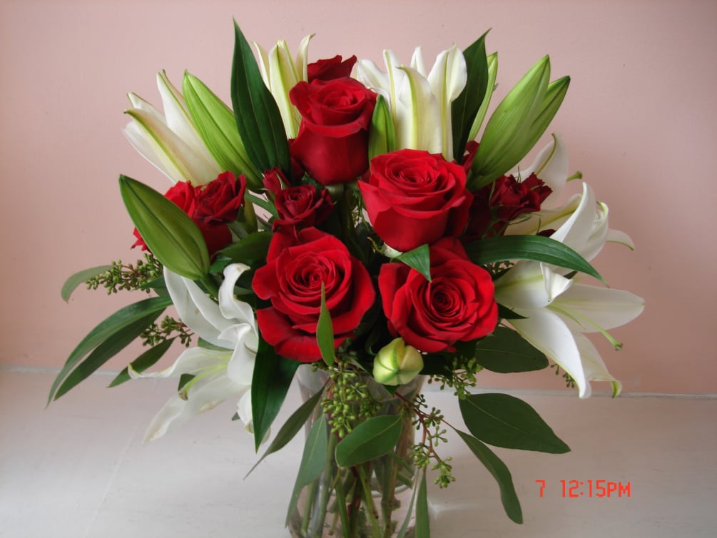 Elegantly arranged Red roses and White Oriental lilies in gathering clear glass