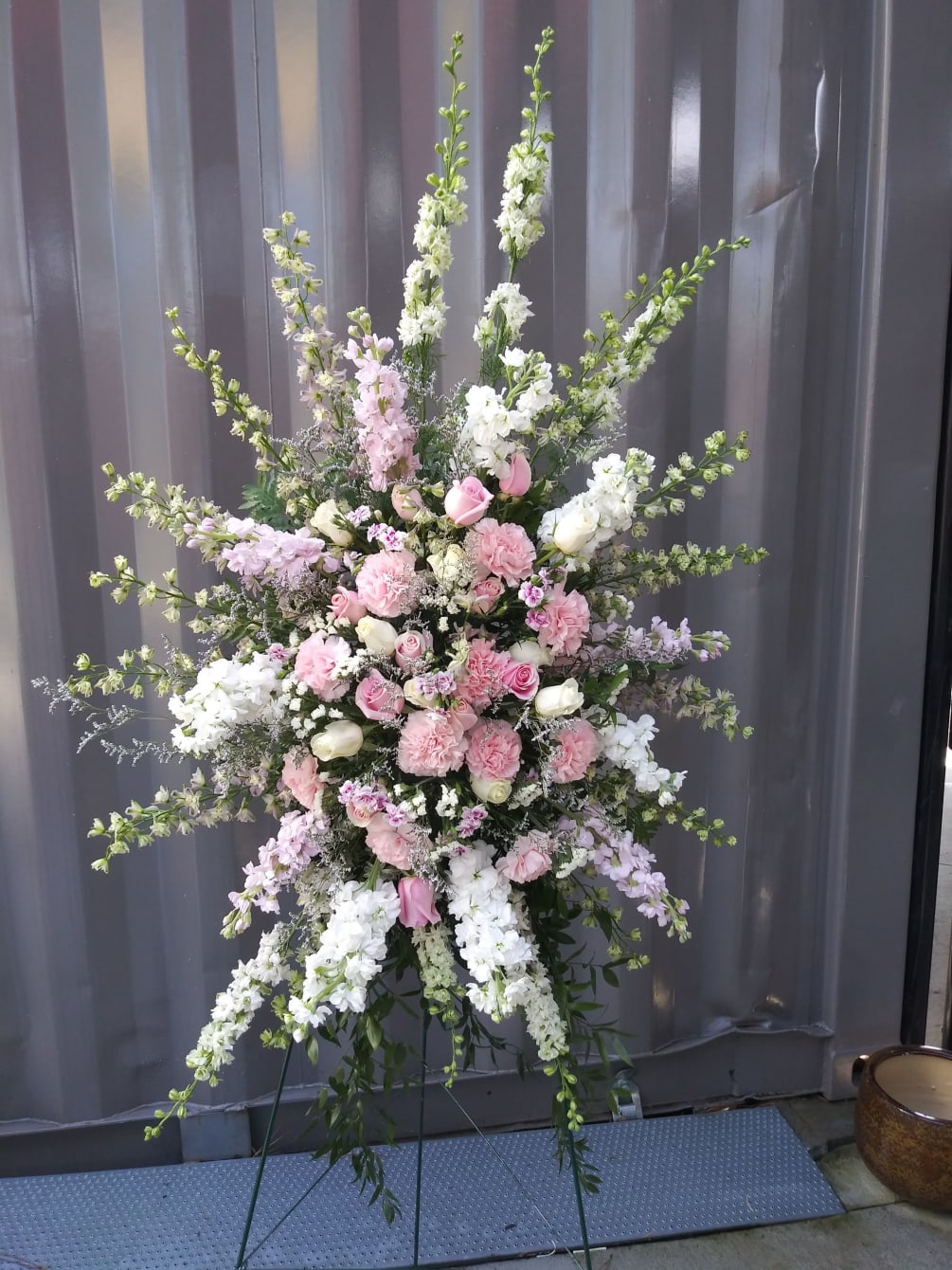 A captivating floral arrangement of soft pink roses and carnations, larkspur, cream