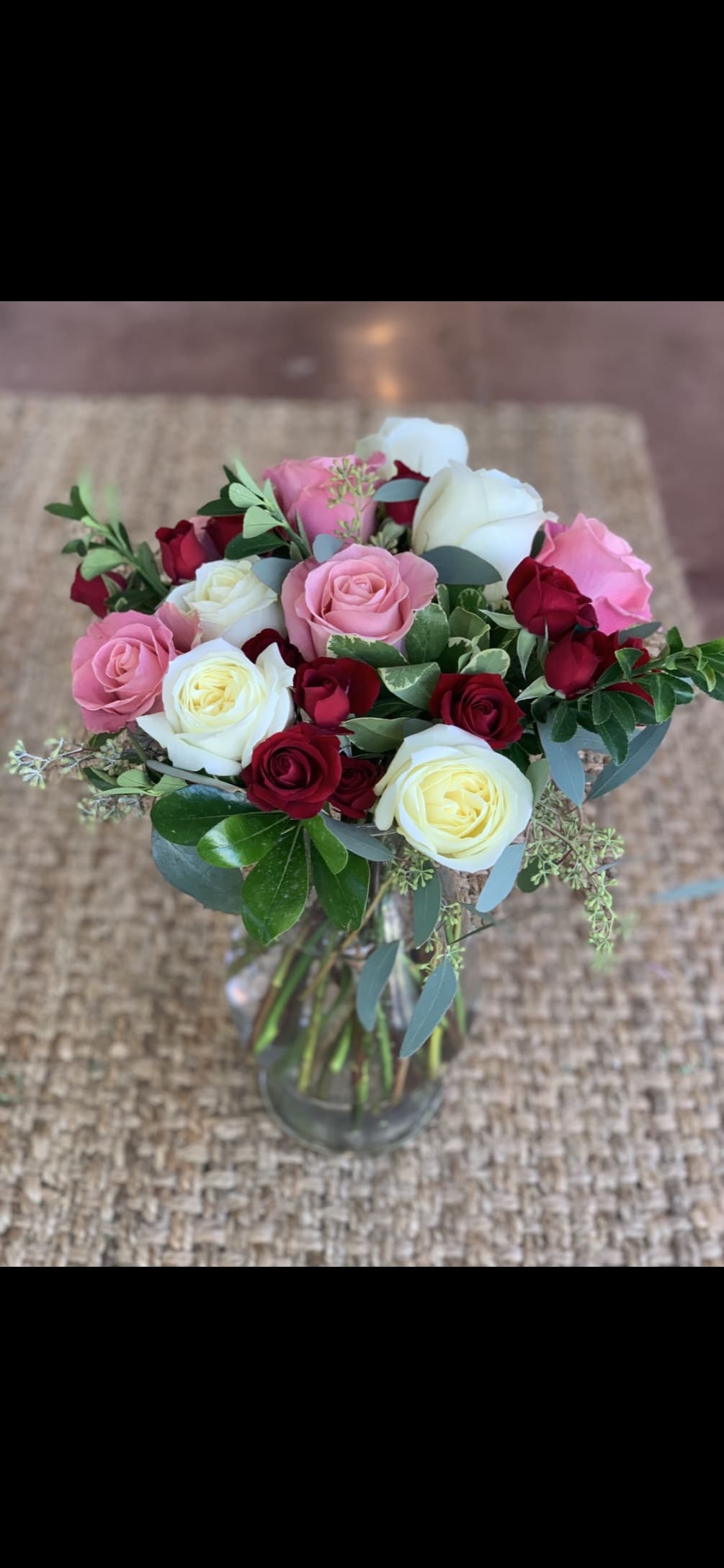 Dozen roses in various colors with greens