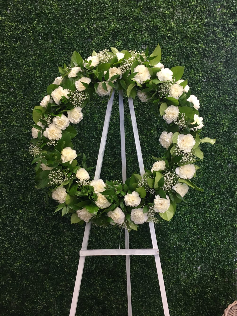 Stunning and quaint floral wreath designed with seasonal white flowers and greens.