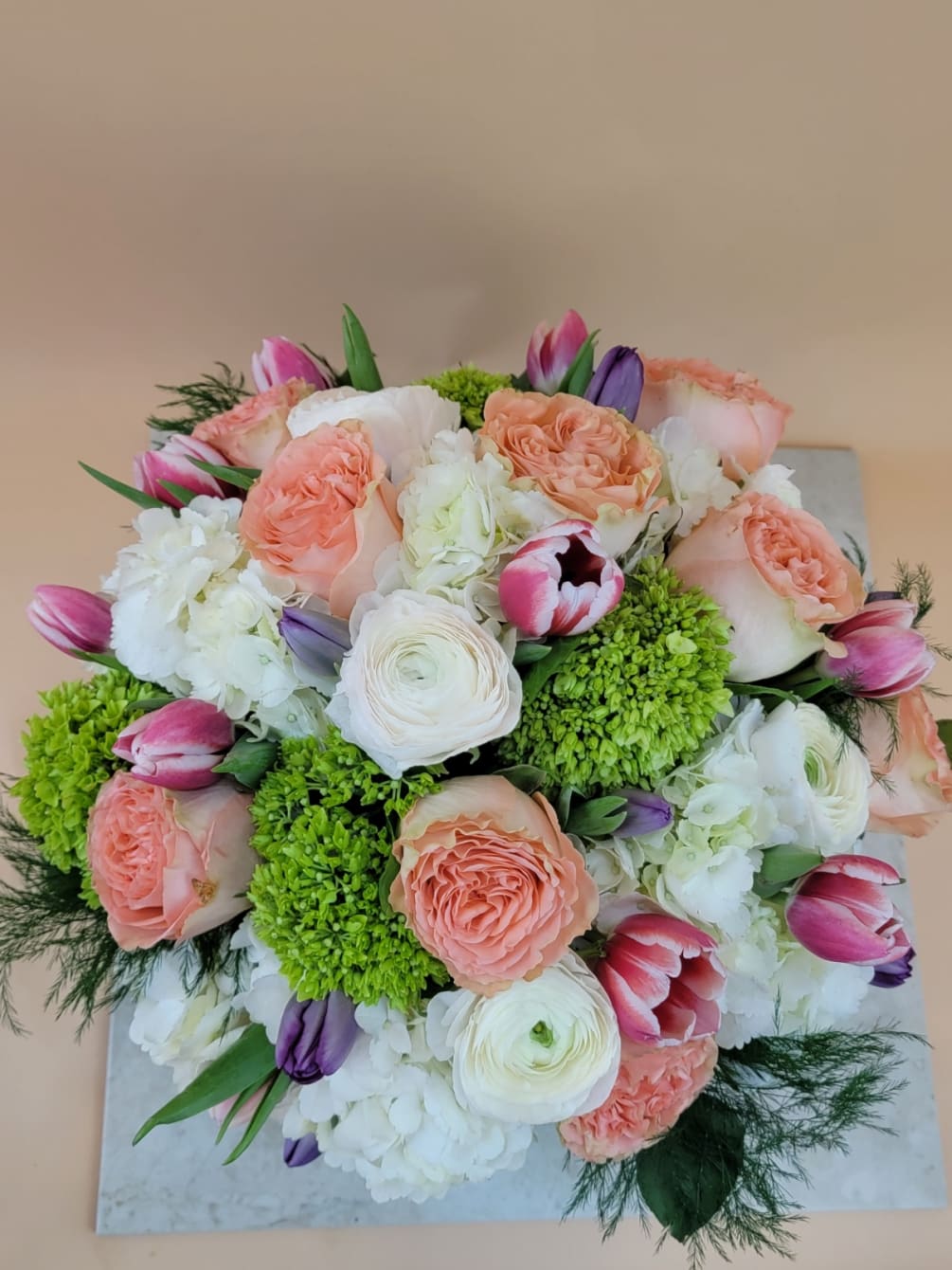 Beautifully arranged roses, ranunculus, tulips and hydrangea in a assortment of colors