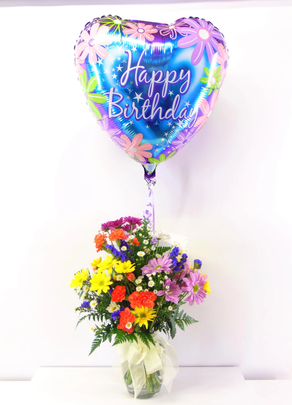 Colorful mixed blooms arranged in a clear glass vase topped off with
