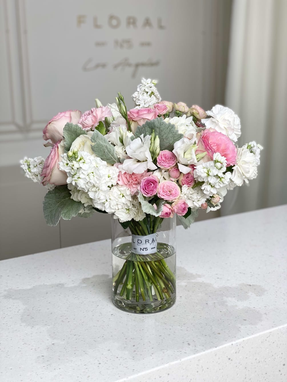 An elegant bouquet with pink roses, white matthiolas and other flowers to