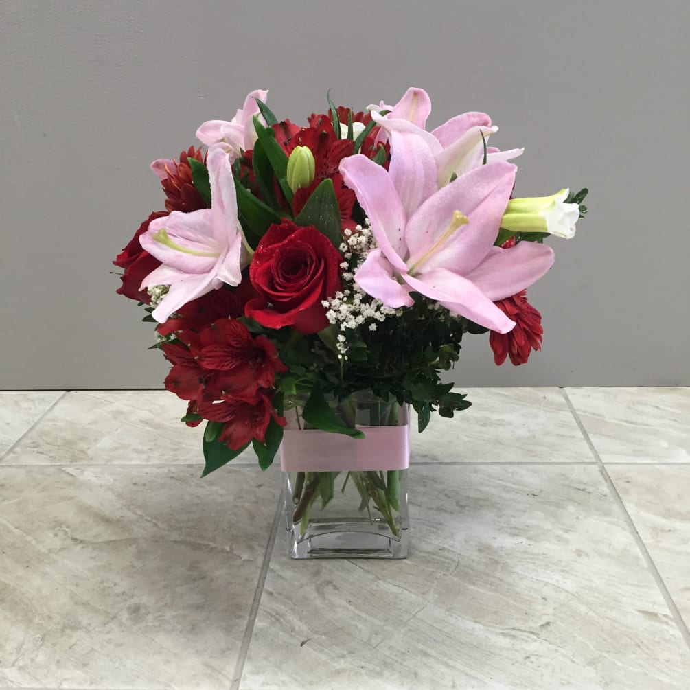 Red and pink mixed flowers in a rectangle clear glass vase with