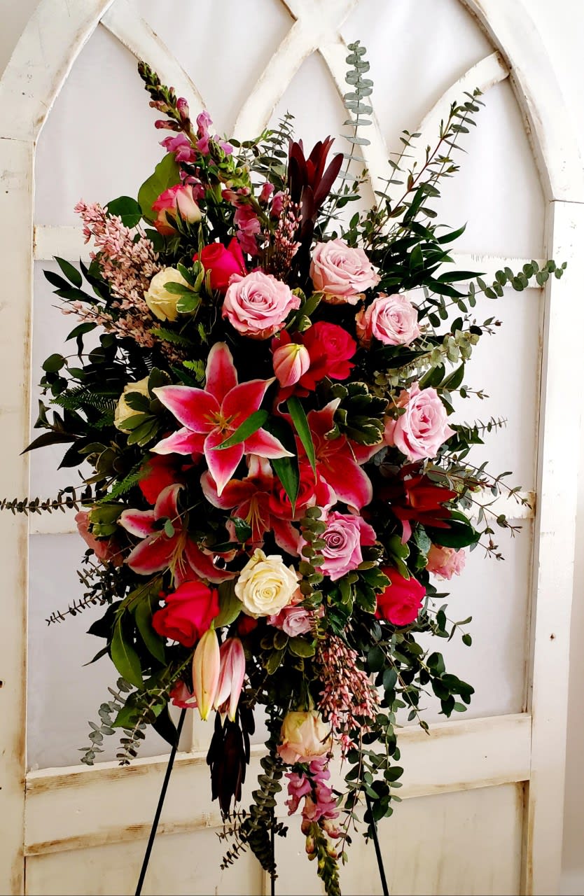 Standing Spray Tribute includes roses, lilies, snapdragons and beautiful greenery.  Delivered