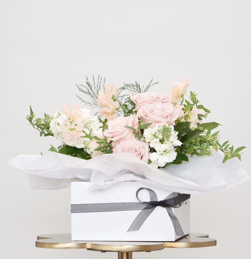 This arrangement comes in a white vase, set in a box with