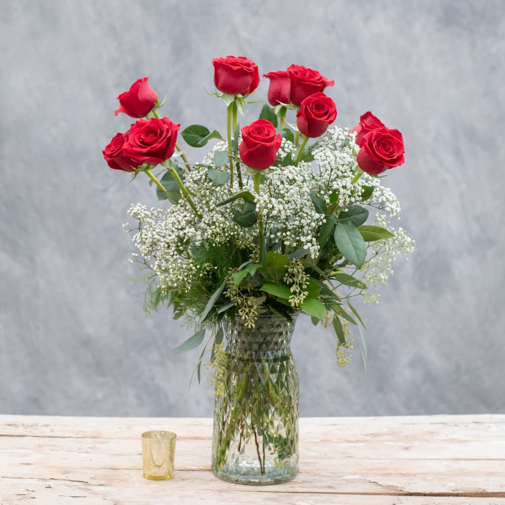One dozen long stemmed red roses classically arranged in a tall, tapered