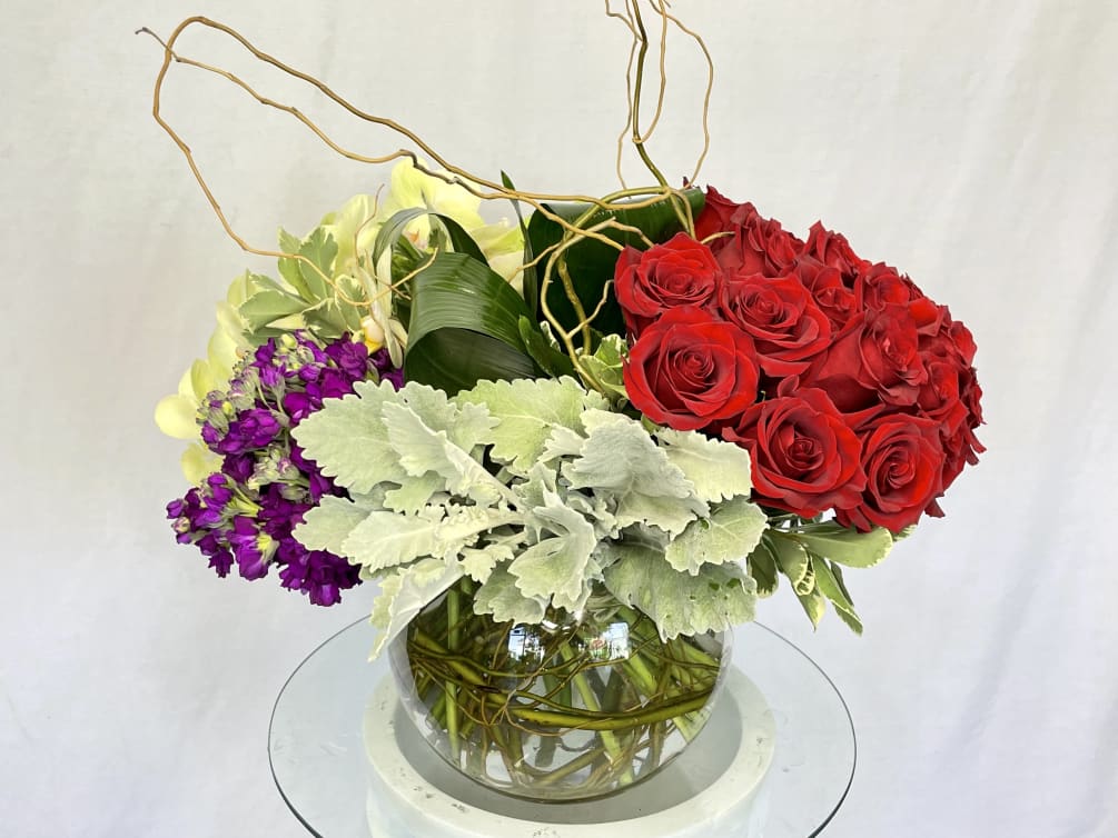 A stunning arrangement consisting of Red Roses, Purple Stock, Cymbidium Orchids, Dusty
