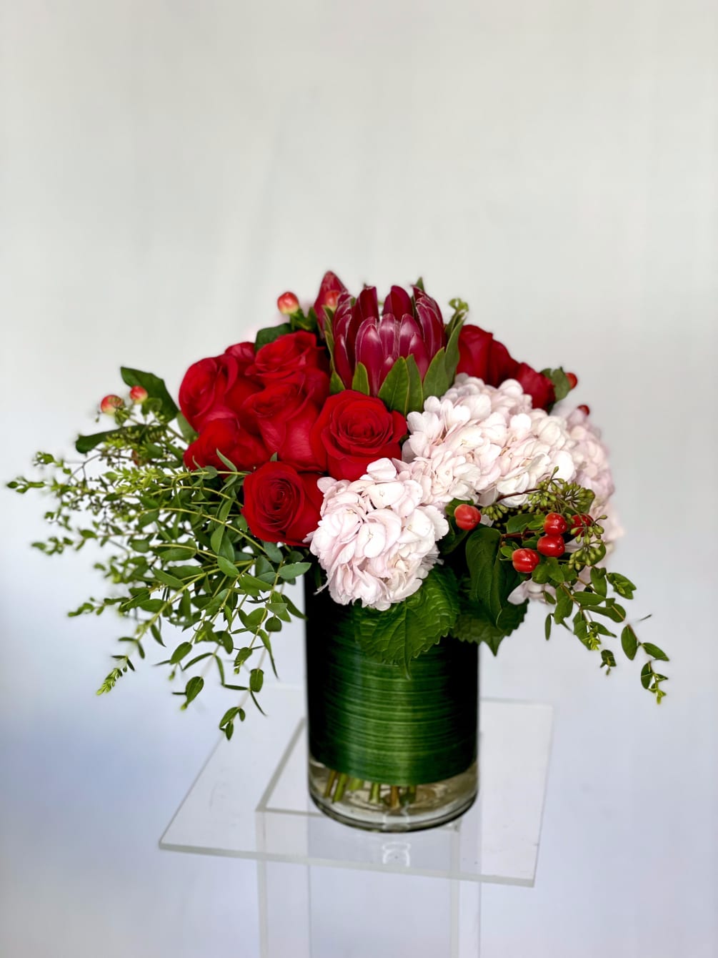 An amazing arrangement consisting of red roses, pink or green hydrangeas, and
