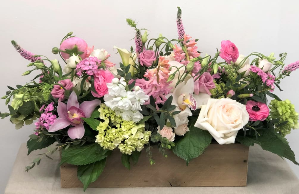 An extravagant arrangement of dazzling flowers in a large oblong planter box.