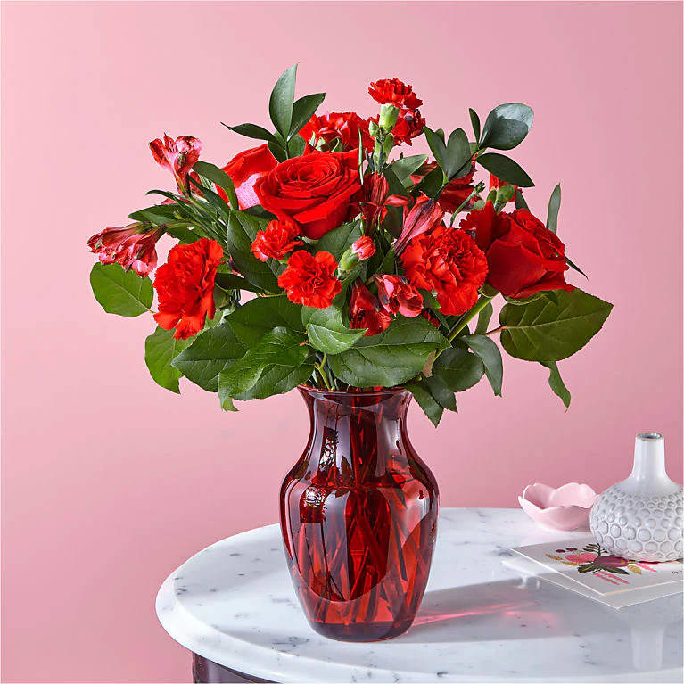 Amplified by a ruby red vase, this rich arrangement of roses, carnations
